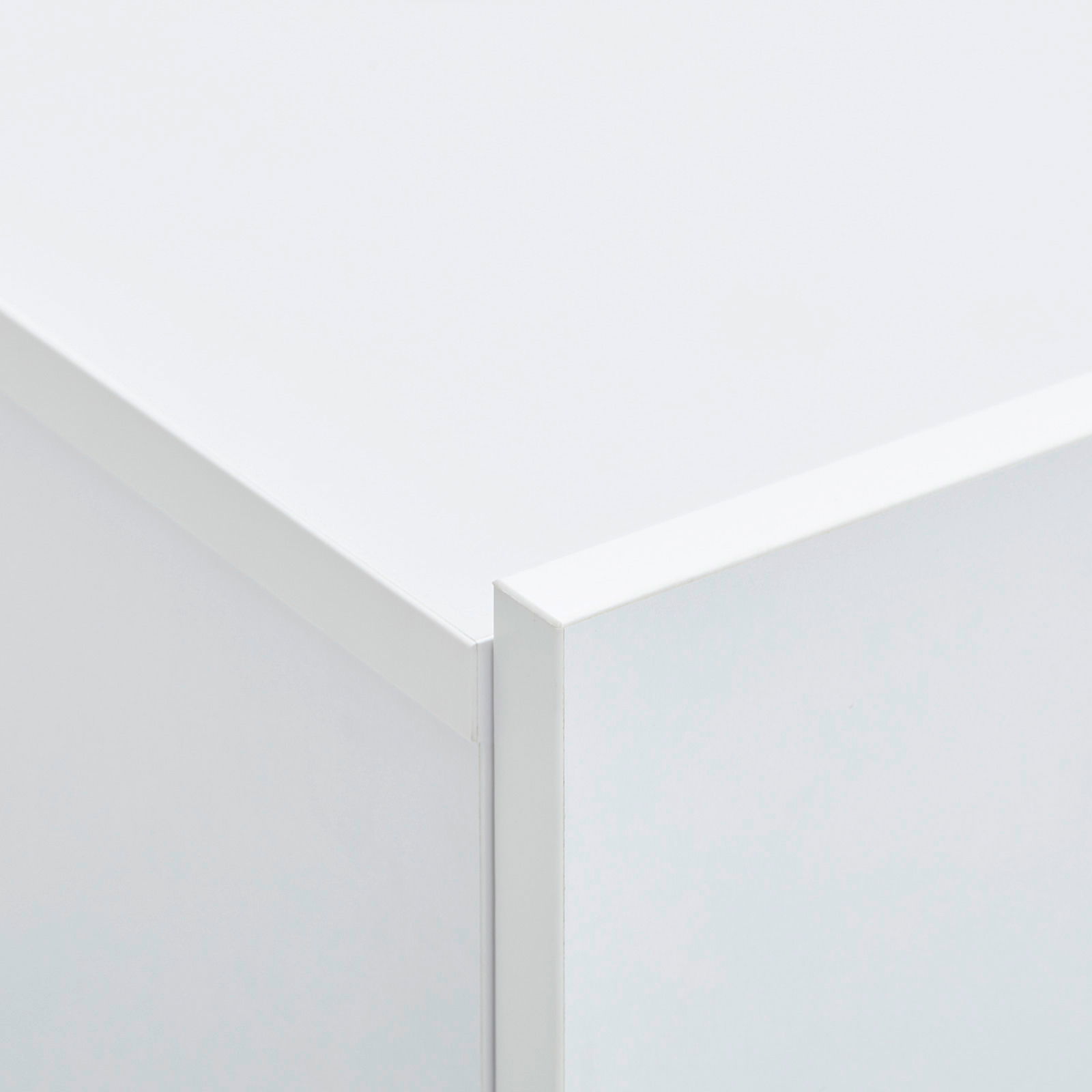 Nahaufnahme einer Ecke eines weißen Hängeschuhschranks, perspektivisch von oben fotografiert.