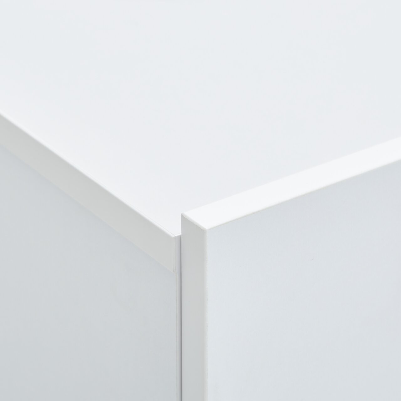 Close-up van een hoek van een witte hangende schoenenkast, vanuit een perspectief van bovenaf gefotografeerd.