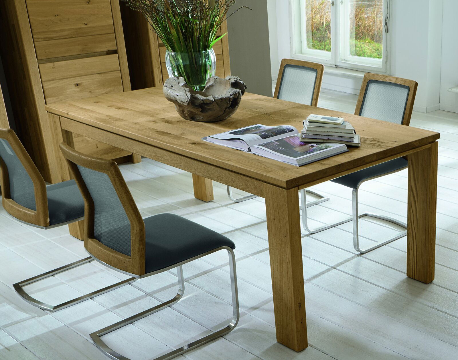 Wöstmann Markenmöbel Esstisch WET 3090 SOLEO 3000 Esstisch aus Holz mit vier Stühlen, dekoriert mit einer Vase und Büchern, seitliche Perspektive