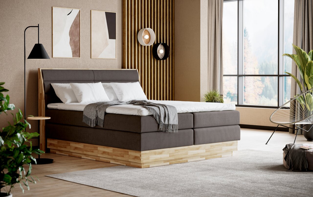 Modernes Boxspringbett in einem stilvollen Schlafzimmer mit Holzdetails und großen Fenstern, seitliche Perspektive