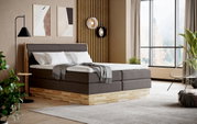 Modern boxspringbed in een stijlvolle slaapkamer met houten details en grote ramen, zijaanzicht