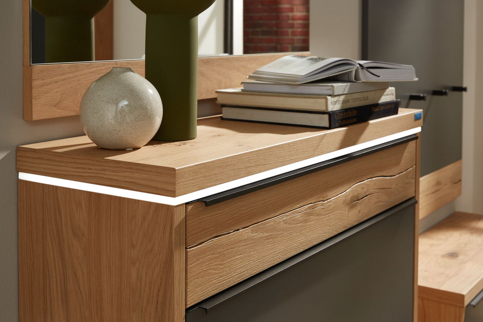 Nahaufnahme eines Hängeschuhschranks mit LED-Beleuchtung, dekoriert mit einer Vase und Büchern, aus einer seitlichen Perspektive.