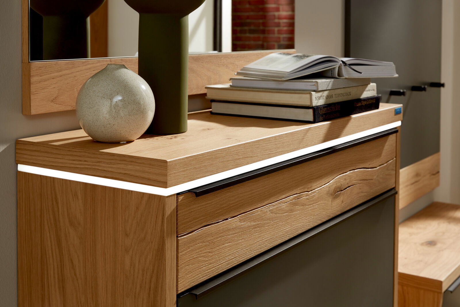 Nahaufnahme eines Hängeschuhschranks mit LED-Beleuchtung, dekoriert mit einer Vase und Büchern, aus einer seitlichen Perspektive.