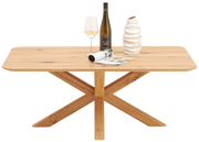 Holz-Couchtisch LINUS von Linea Natura mit X-förmigem Gestell, dekoriert mit einer Vase, einer Weinflasche und einem Glas, aus der Frontalperspektive.