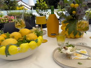 Sommerliche Tischdekoration mit Zitronen, Desserts und Getränken auf der Terrasse.