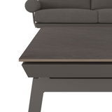 Nahaufnahme eines Lounge-Sets mit grauem Tisch und Sofa im Hintergrund, seitliche Perspektive.