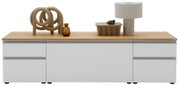Modernes Lowboard/Sideboard in Hellgrau mit Eichenholzplatte, frontale Ansicht; oben Deko mit Skulptur, brauner Glasvase, Schale und Tischlampe vor weißem Hintergrund.