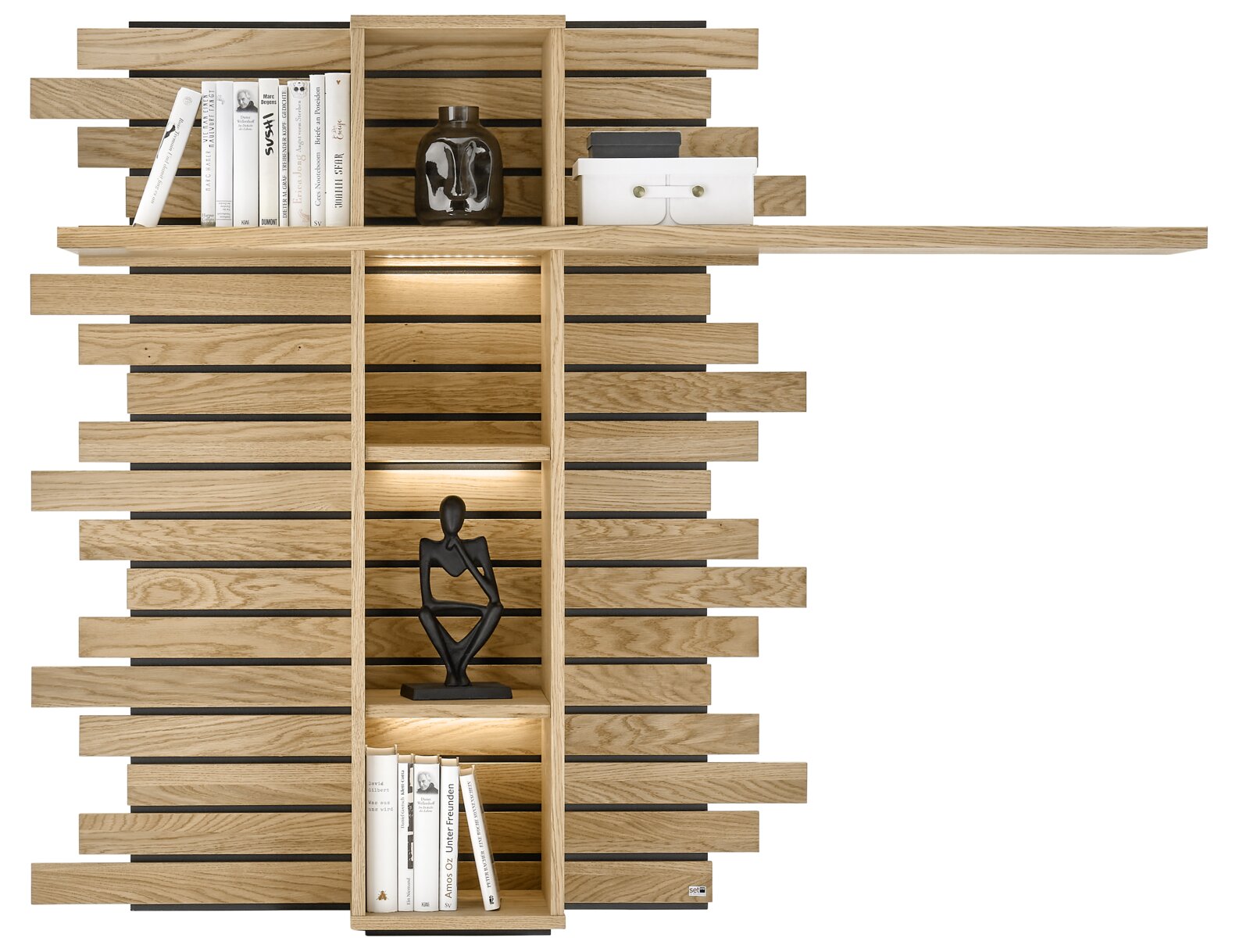 Set one by Musterring Hängepaneel SET ONE JACKSON Modernes Wandregal aus hellem Holz mit horizontalen Lamellen, integrierten Fächern und LED-Beleuchtung, dekoriert mit Büchern, Vase und Figur – Frontansicht.