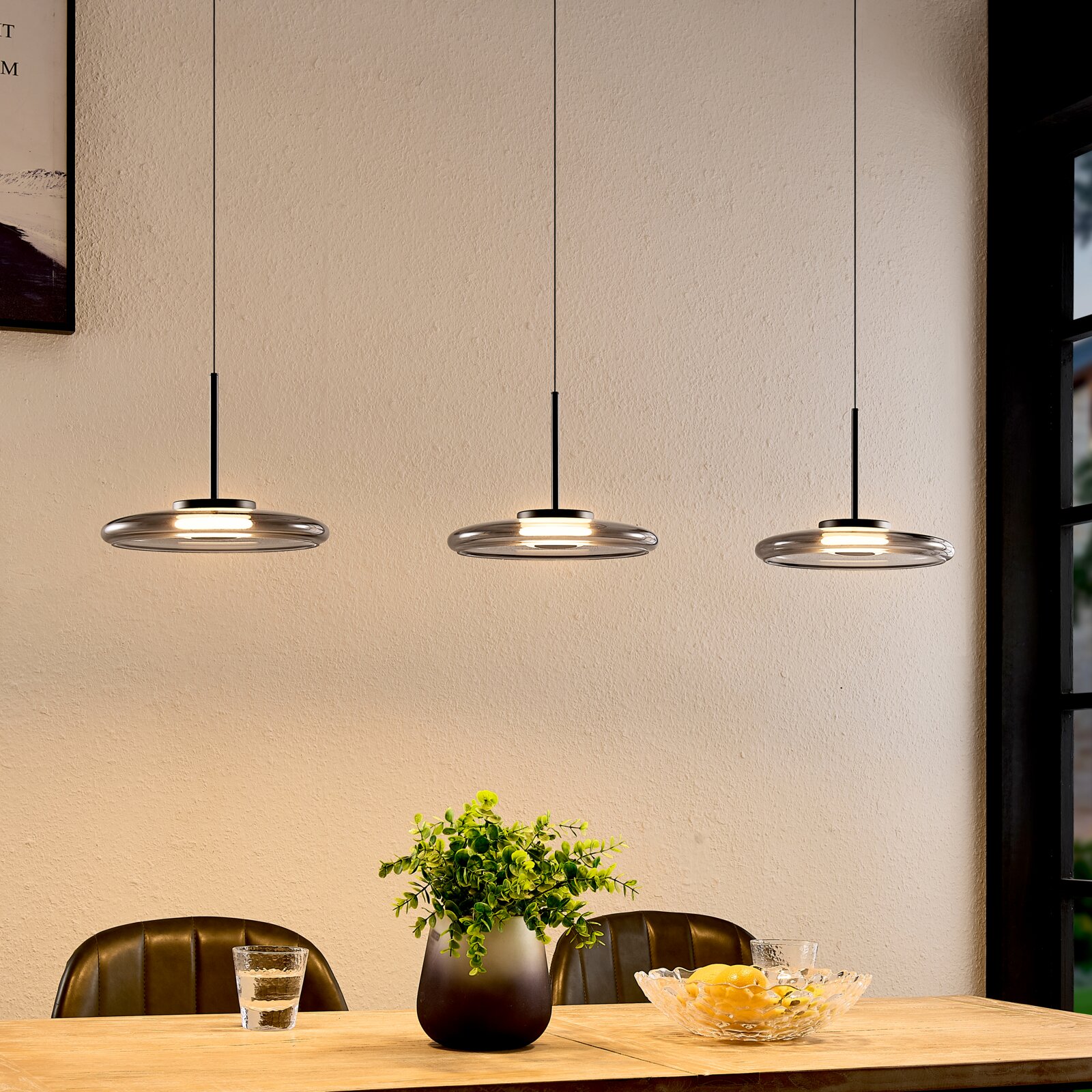Novel LED-Hängeleuchte PENDELLEUCHTE Drei moderne LED-Hängeleuchten in einer gemütlichen Esszimmerumgebung, von der Seite betrachtet.