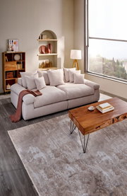 Gemütliches Big-Sofa in einem modernen Wohnzimmer, seitliche Perspektive mit großen Fenstern und stilvoller Dekoration.