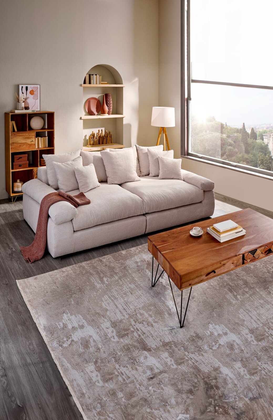 Gemütliches Big-Sofa in einem modernen Wohnzimmer, seitliche Perspektive mit großen Fenstern und stilvoller Dekoration.