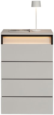 Hochkommode mit vier Schubladen, moderne graue Oberfläche, beleuchtetes Fach oben, Ansicht von vorne, dekoriert mit einer Tischlampe und einem Buch.