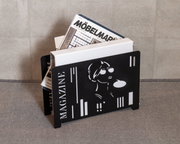 Schwarzer Zeitungsständer mit modernem Design, gefüllt mit Zeitschriften, seitliche Perspektive