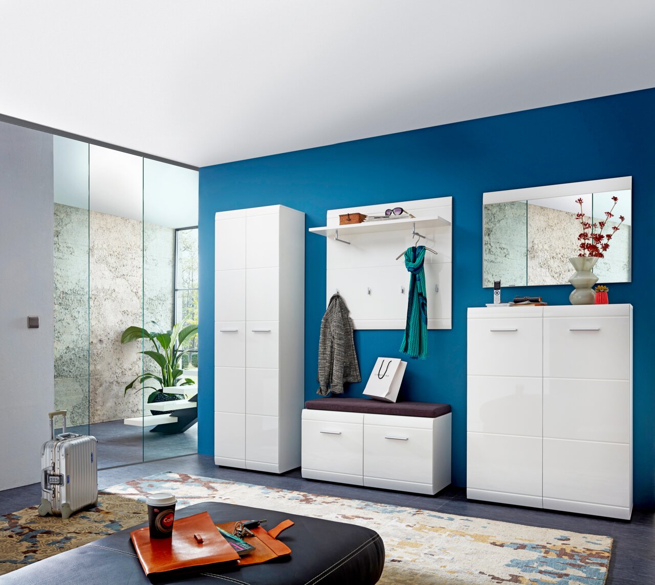 Moderne Garderobeneinrichtung mit weißem Hochglanz-Schuhschrank, Garderobenpaneel mit Ablage und Haken, Sitzbank mit Kissen und großem Spiegel, Perspektive von vorne