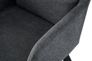 Nahaufnahme eines dunkelgrauen, gepolsterten Stoffsessels mit Armlehne und Sitzfläche, schräg von vorne/rechts aufgenommen