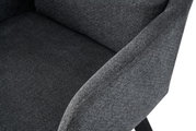 Nahaufnahme eines dunkelgrauen, gepolsterten Stoffsessels mit Armlehne und Sitzfläche, schräg von vorne/rechts aufgenommen