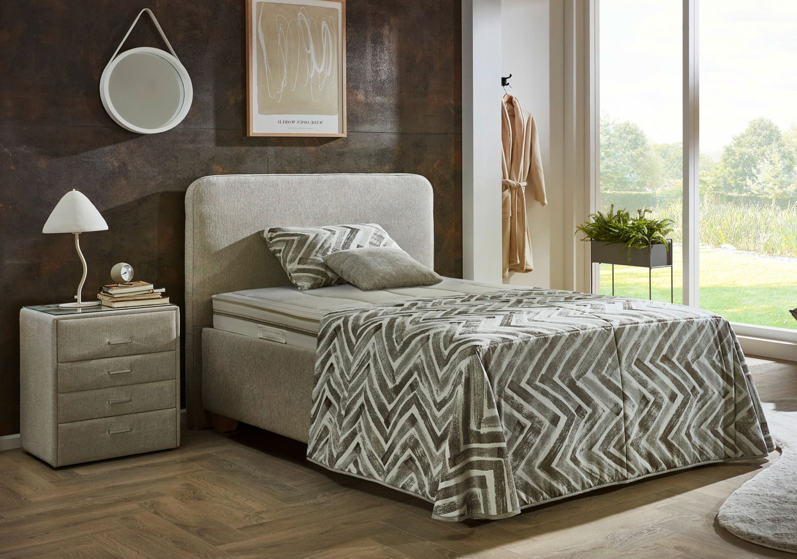 Modernes Polsterbett in einem stilvollen Schlafzimmer, seitliche Perspektive mit Nachttisch und Lampe.