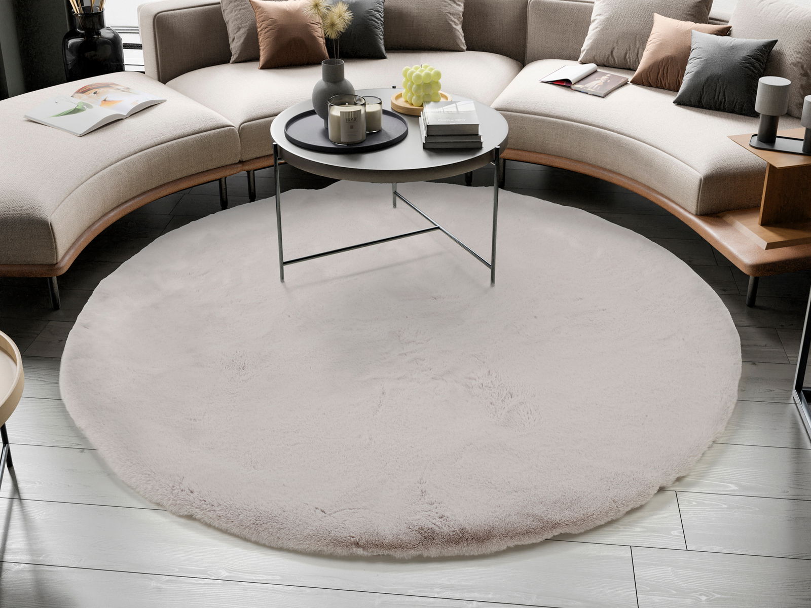 Runder, cremefarbener Fellteppich in einem modernen Wohnzimmer, von oben betrachtet, unter einem runden Couchtisch platziert.