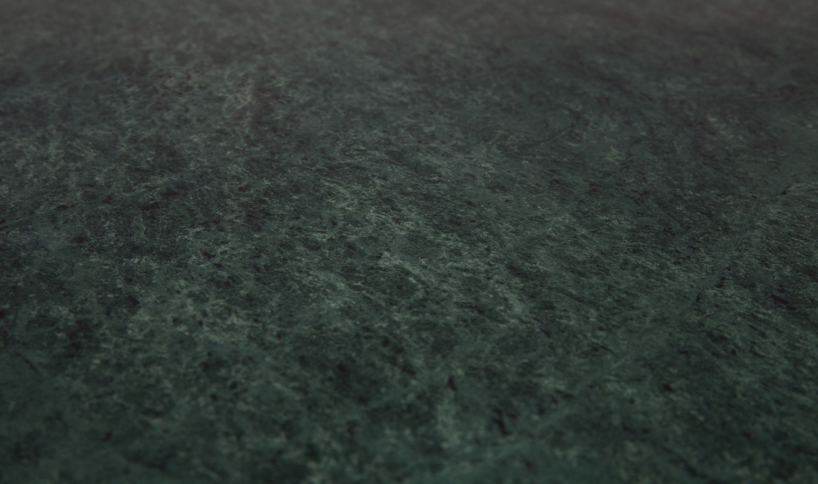Nahaufnahme der Oberfläche eines Beistelltisches mit dunkelgrüner, marmorierter Textur.