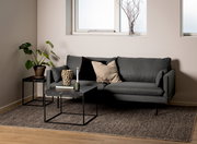 Moderner Couchtisch mit schwarzer Marmoroptik und Metallgestell, frontal vor einem grauen Sofa in einem stilvoll eingerichteten Wohnzimmer.