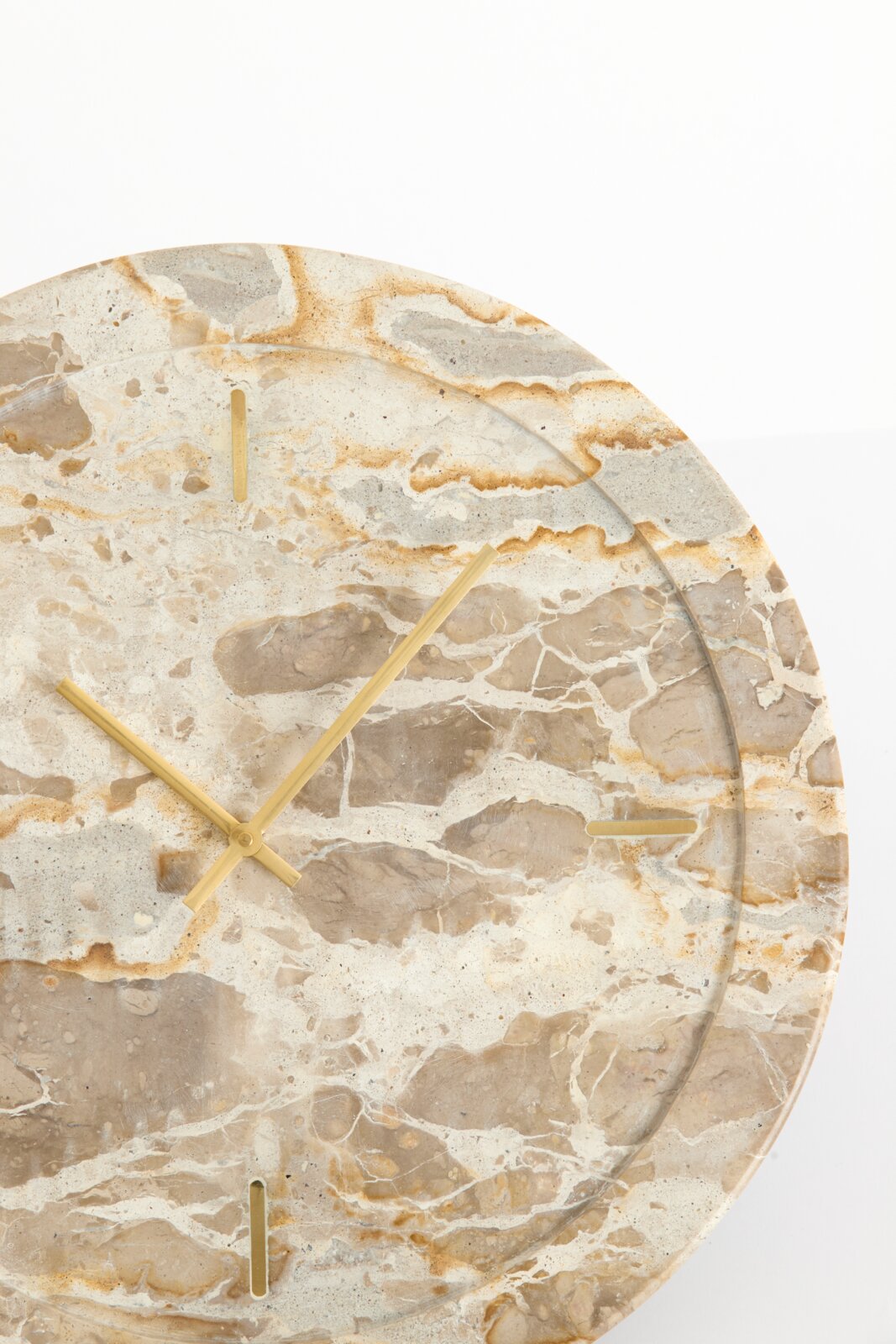 Close-up in vooraanzicht van een ronde wandklok met beige marmerpatroon, goudkleurige wijzers en minimalistische uurmarkeringen.