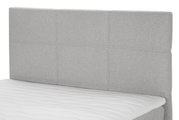 Graues Boxspringbett mit gepolstertem Kopfteil, seitliche Perspektive
