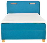Frontale Ansicht eines blauen Boxspringbetts Moderano HELIOS mit weißer Matratze und Holzfüßen.