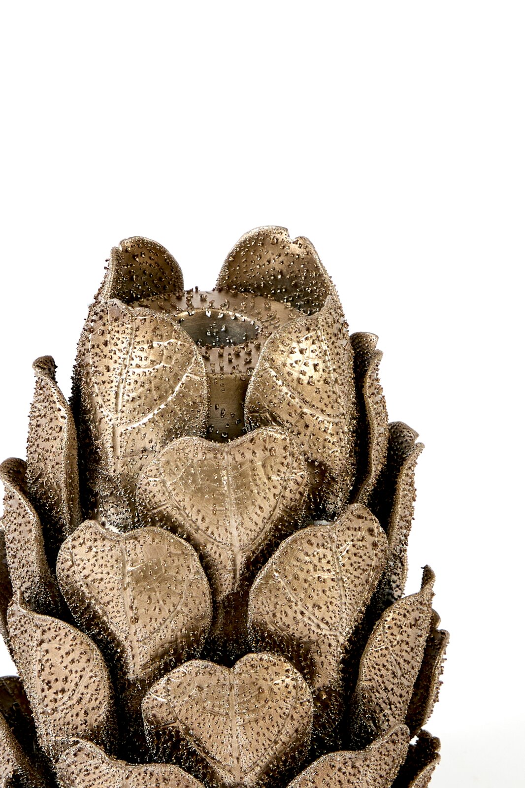 Close-up in vooraanzicht van een goudkleurige decoratieve artisjok met gedetailleerde, reliëfrijke bladeren op een witte achtergrond