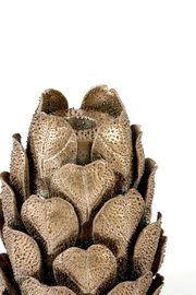 Close-up in vooraanzicht van een goudkleurige decoratieve artisjok met gedetailleerde, reliëfrijke bladeren op een witte achtergrond
