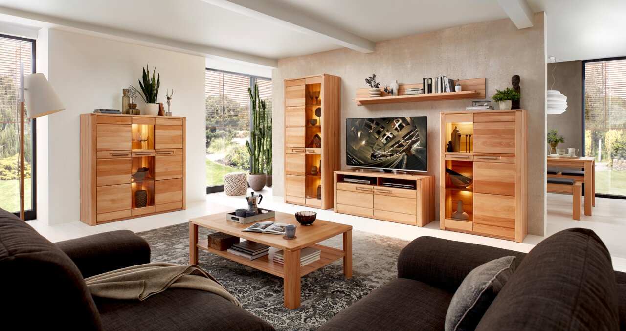 Woonkamer met moderne houten meubels, waaronder een tv-kast, vitrinekasten en een salontafel, gezien vanuit een gezellige zithoek.
