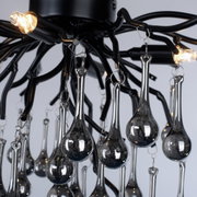 Nahaufnahme der Deckenleuchte ICICLE mit eleganten, tropfenförmigen Glaselementen und schwarzem Metallrahmen, von unten betrachtet.