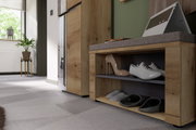 Houten kleedkamerbank met grijze bekleding, zijaanzicht, met schoenen op twee niveaus en een laptop op de zitting.