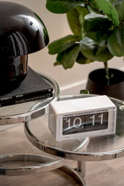 Retro Flip-Uhr von KARLSSON auf einem modernen Glastisch, seitliche Perspektive.