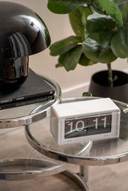 Retro Flip-Uhr von KARLSSON auf einem modernen Glastisch, seitliche Perspektive.