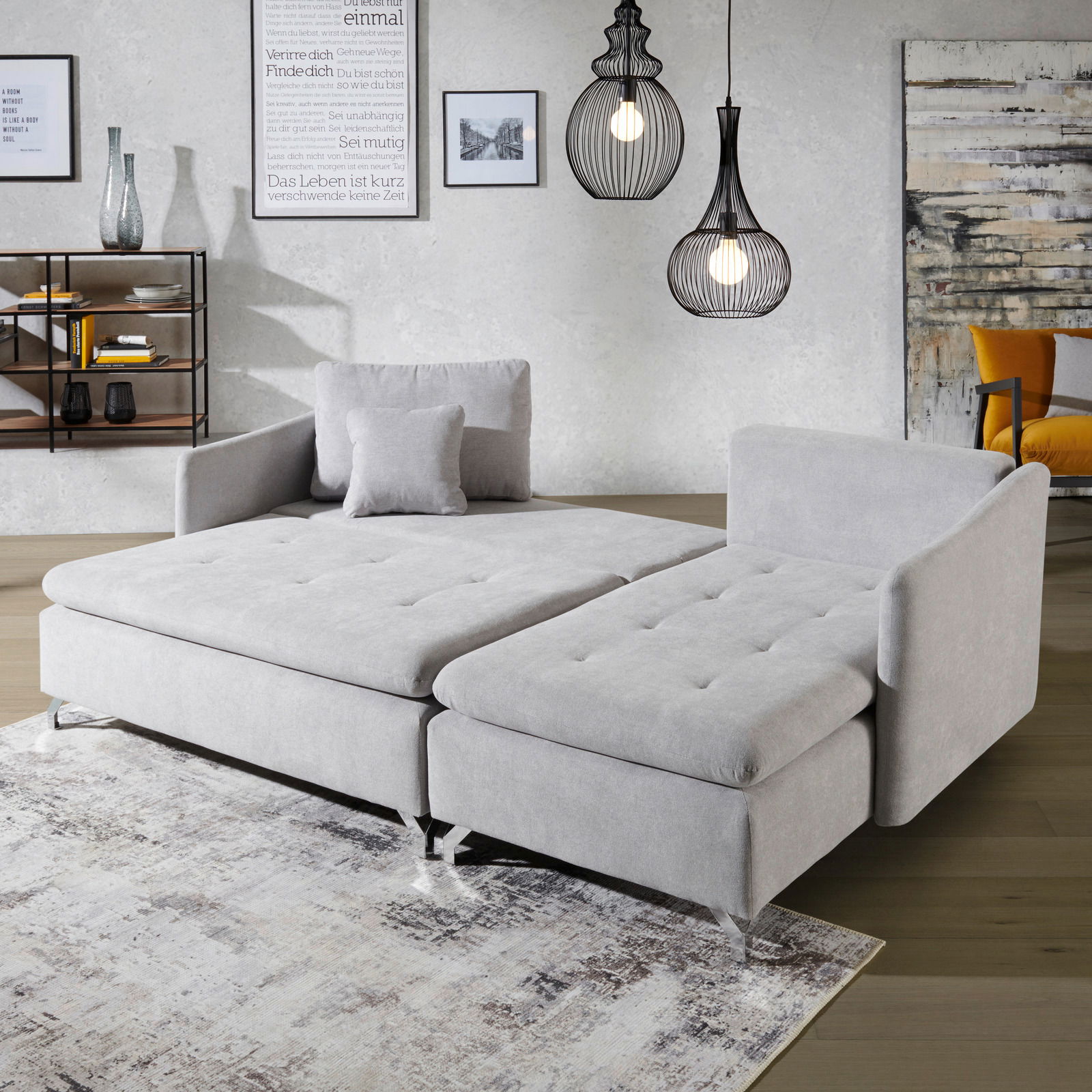 Graue Rundecke in einem modernen Wohnzimmer, von vorne betrachtet, mit dekorativen Kissen und stilvollen Hängeleuchten im Hintergrund.