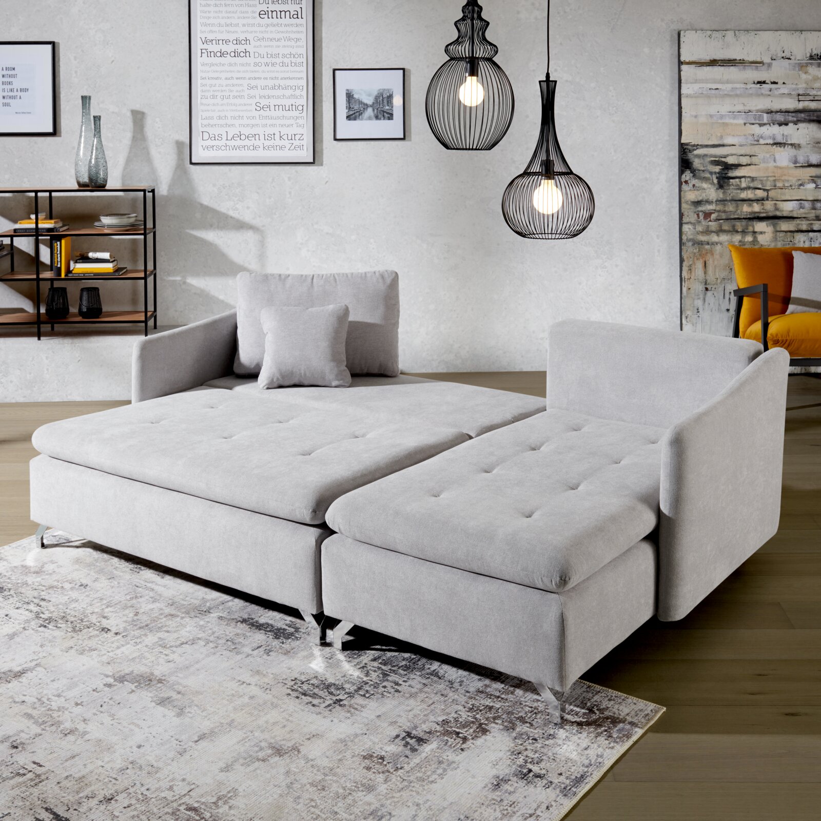 Graue Rundecke in einem modernen Wohnzimmer, von vorne betrachtet, mit dekorativen Kissen und stilvollen Hängeleuchten im Hintergrund.