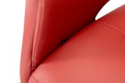 Close-up van een rode leren relaxfauteuil, met de nadruk op de naad tussen de rugleuning en de zitting, gezien vanuit de zijkant.