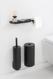 Schwarzer Toilettenpapierhalter mit Ablage, darauf ein Duftspender und ein Smartphone, seitliche Perspektive.