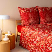 Rote Bettwäsche mit Paisley-Muster auf einem Bett, seitliche Perspektive