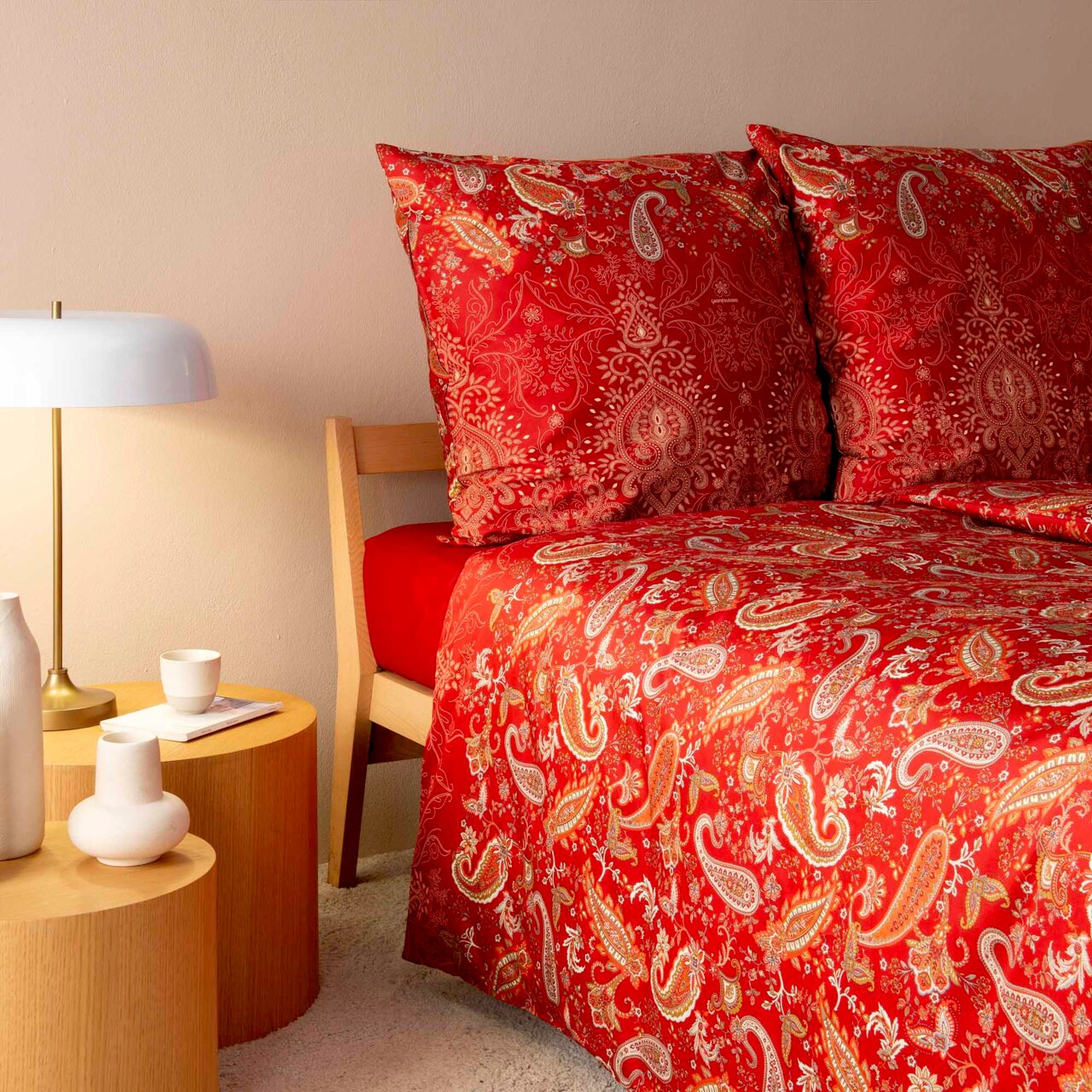 Rote Bettwäsche mit Paisley-Muster auf einem Bett, seitliche Perspektive