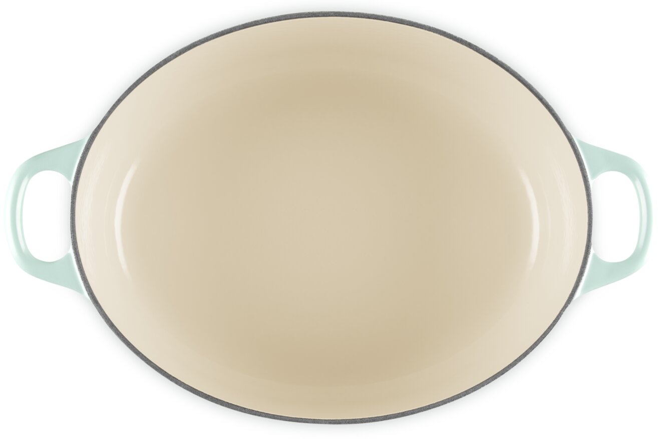 Ovaler, cremefarbener Bräter/Schmortopf mit helltürkisen Griffen, Draufsicht von oben auf weißem Hintergrund