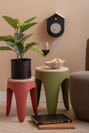 Moderne Wanduhr Grato in Schwarz und Weiß, aufgehängt an einer beigen Wand, mit einem Pendel. Perspektive von vorne, neben dekorativen Elementen wie einem Pflanzenständer und einem Weinglas.