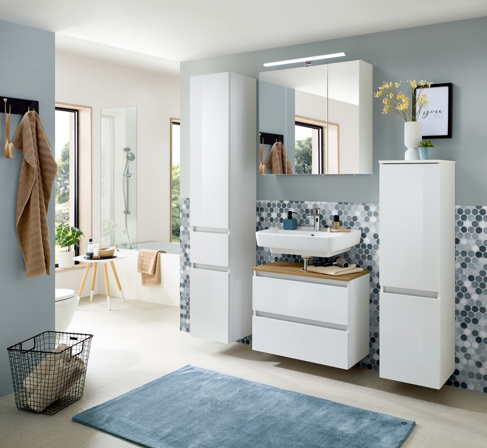 Modernes weißes Badezimmermöbel-Set mit Spiegelschrank und LED-Aufbauleuchte, Waschtisch mit zwei Schubladen sowie zwei Hochschränken, frontal in leichter Schrägansicht von vorn fotografiert