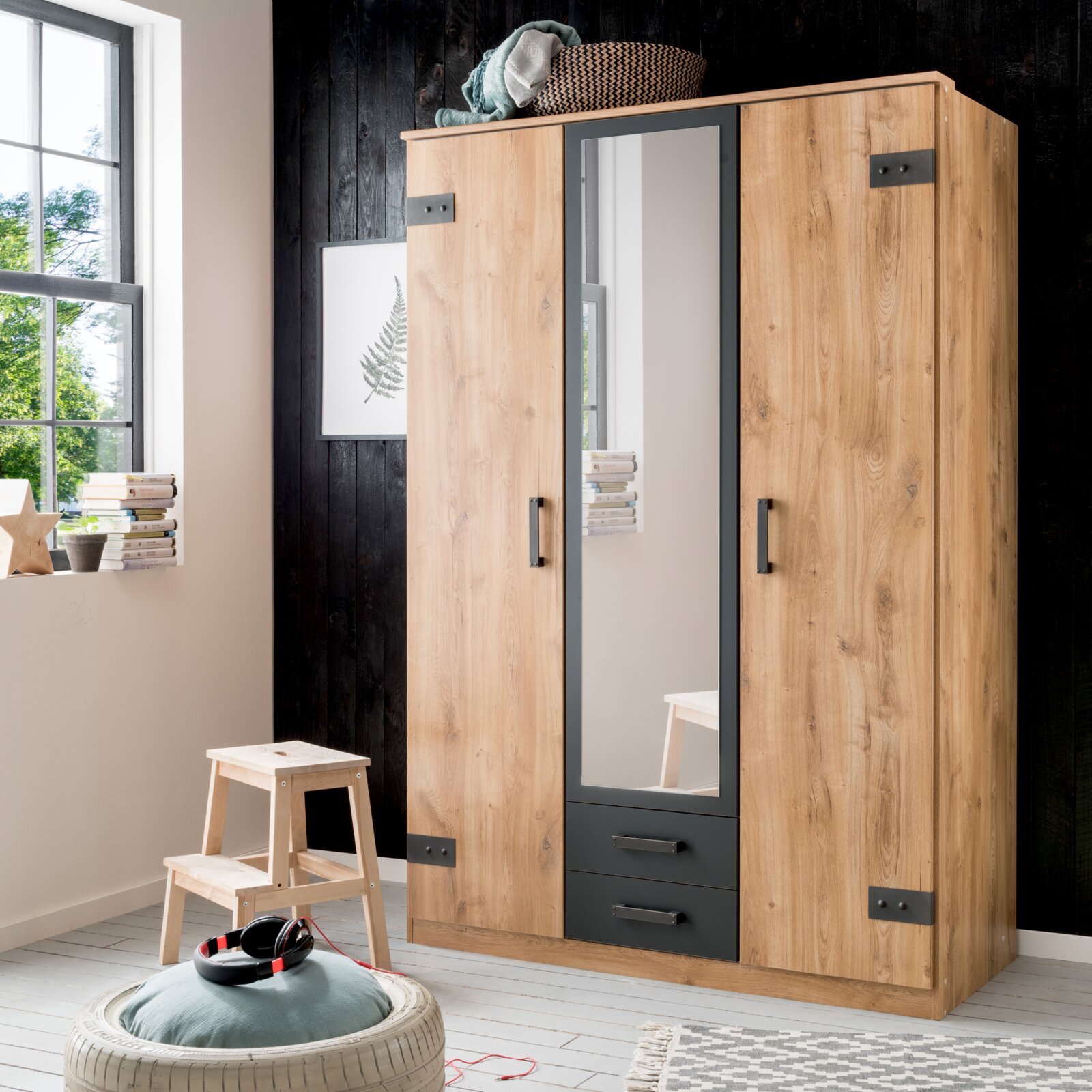 Drehtürenschrank mit drei Türen, mittlere Tür mit Spiegel, aus Holzoptik mit schwarzen Akzenten, frontal abgebildet in einem modernen Raum.