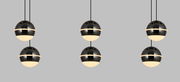 Moderne LED-Pendelleuchte mit kugelförmigem Design, in einer frontalen Perspektive gezeigt, bestehend aus drei schwarzen, glänzenden Kugeln mit leuchtenden unteren Hälften, aufgehängt an dünnen Kabeln.