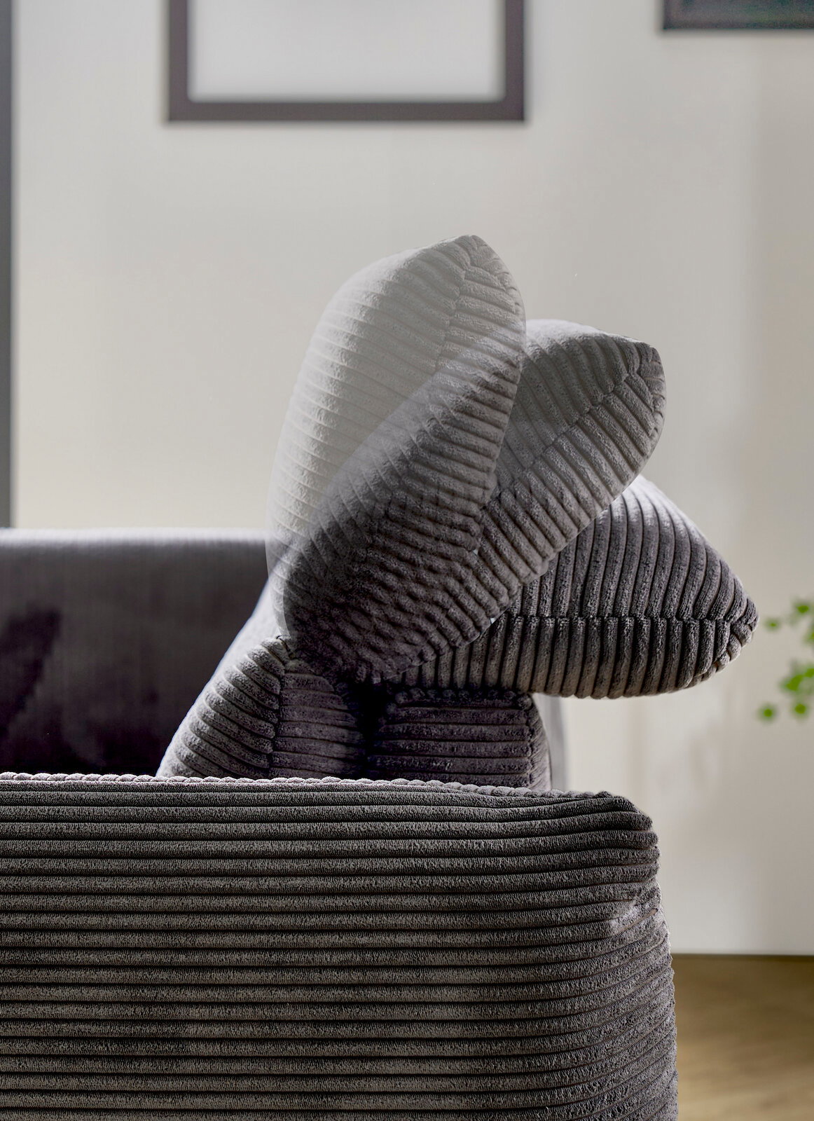 Nahaufnahme eines grauen Megasofas mit geripptem Stoffbezug, seitliche Perspektive