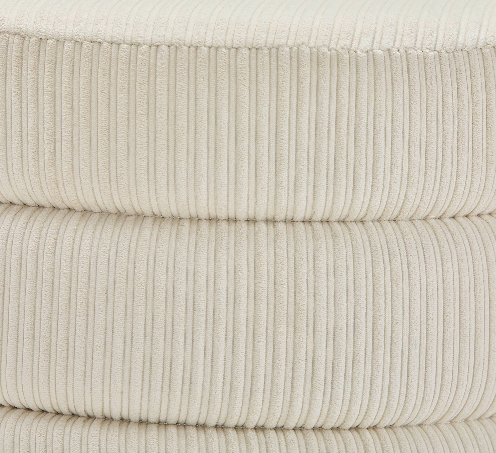 Nahaufnahme eines cremefarbenen, gerippten Hockers aus Stoff, seitliche Perspektive