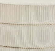 Nahaufnahme eines cremefarbenen, gerippten Hockers aus Stoff, seitliche Perspektive