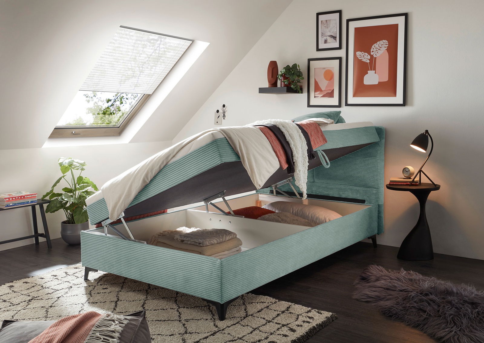 Boxbett mit aufklappbarem Stauraum, seitliche Perspektive, in einem modern eingerichteten Schlafzimmer unter einer Dachschräge.