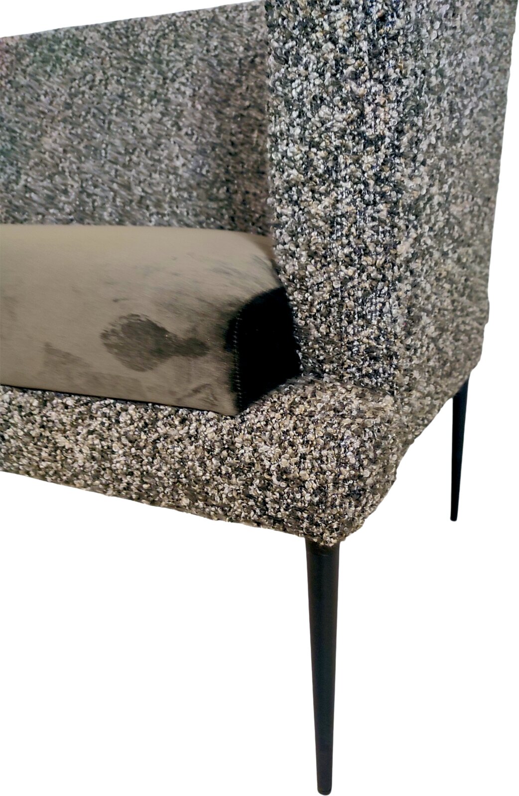 Gepolsterter Sessel mit grauem Bouclé-Bezug, schwarzem Metallfuß und beigem Kissen, Detailansicht aus schräger Seitenperspektive
